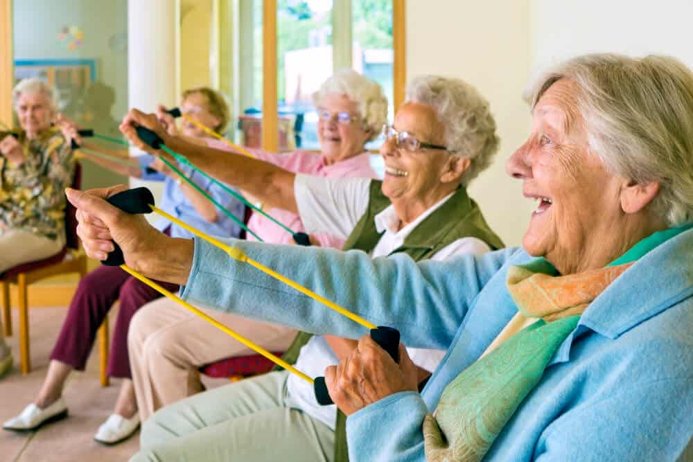 Elderly residents enjoying a seated exercise session together in a care home